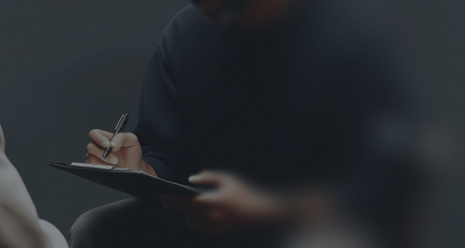 A person holding a pen and writing on a piece of paper.